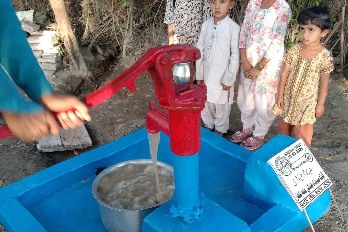 Children gathered around a newly installed hand pump in a rural village in Sindh