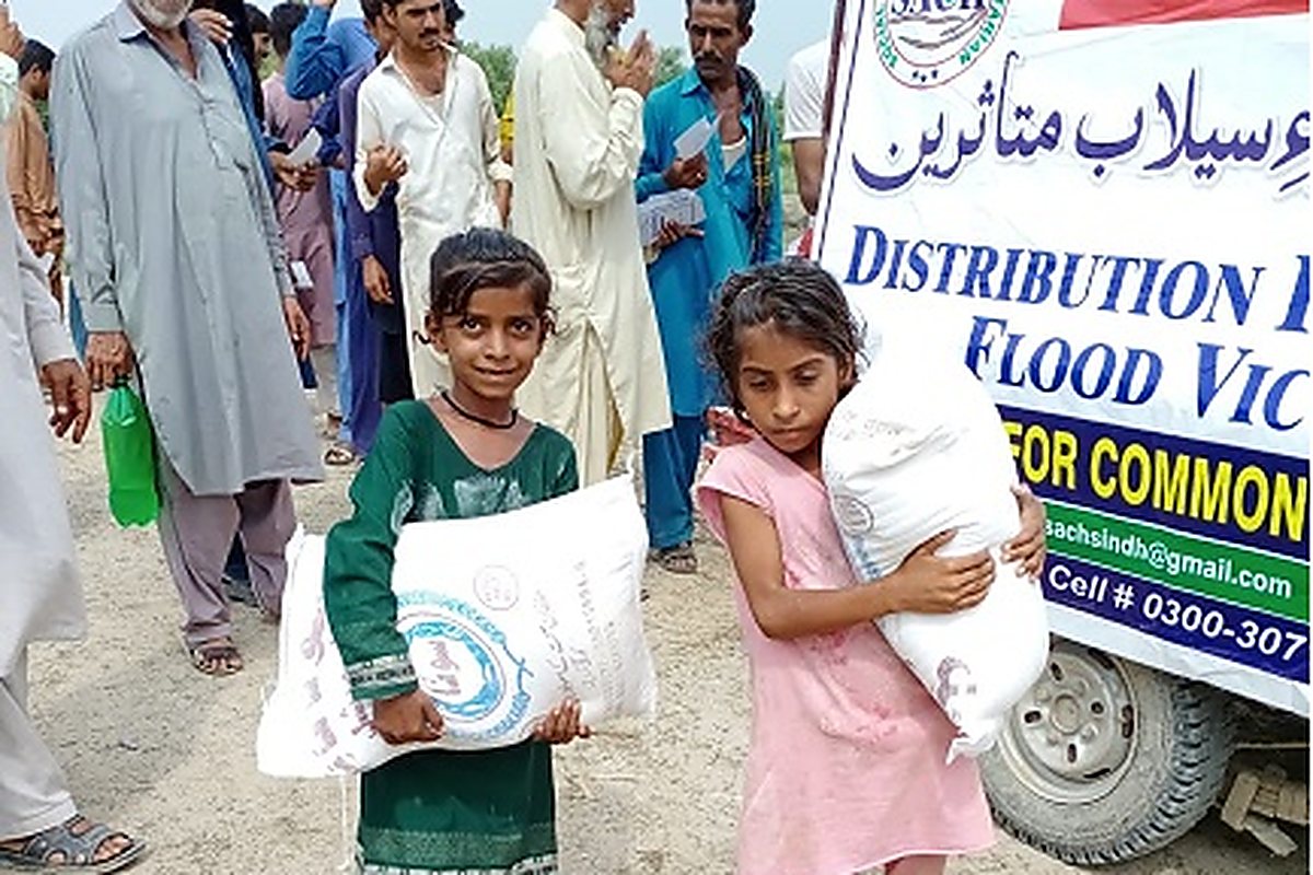 Children carrying SACH ration bags at a flood relief distribution point in Sindh